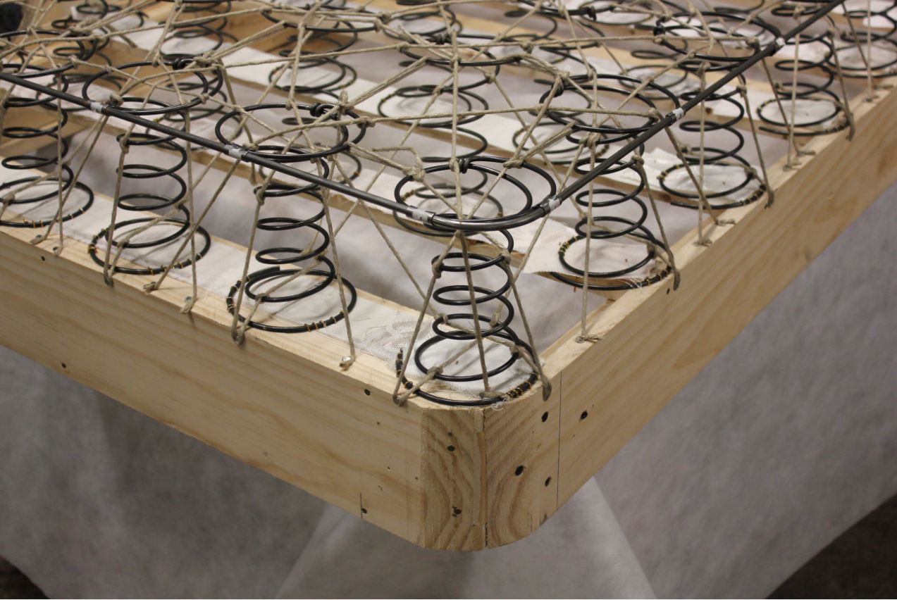 A real hand-tied sprung base under construction. Illustrative archive photograph; not a Sprinqs product.